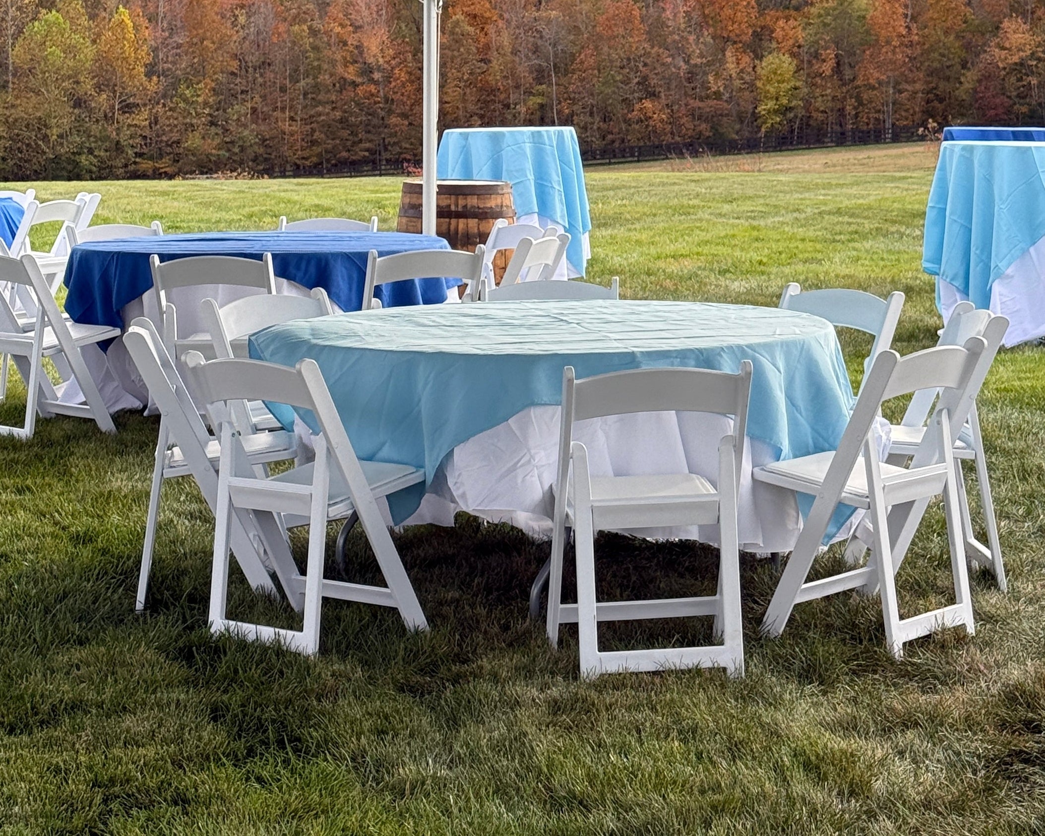 White chairs stacked under a large white tent with a scenic background.